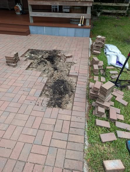 Sunken brick pavers lifted out, showing the settled base underneath